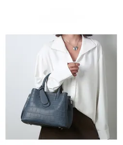 Detail of navy blue faux crocodile embossed leather handbag with metallic studs