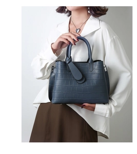 Detail of dark blue crocodile pattern handbag held by model in professional studio setting