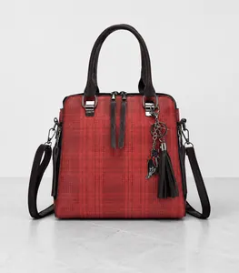 Detail of red checkered handbag with black cat charm and elegant tassel pendant