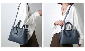 Detailed view of dark blue crocodile embossed handbag with adjustable shoulder strap