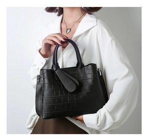 Detail of black crocodile embossed tote bag texture with elegant handle and metal hardware