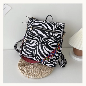 Détail du sac à dos zébré avec bandoulière tissée colorée dans un décor intérieur doux