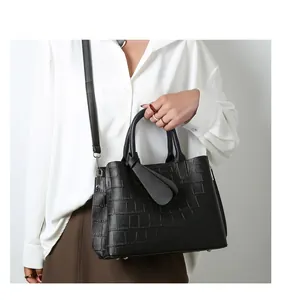 Detail view of black crocodile pattern handbag with elegant top handle and knot decor