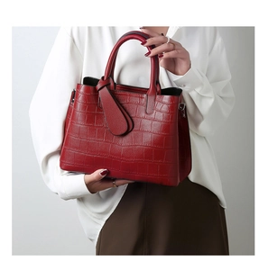 Detailed shot of vibrant red embossed crocodile leather texture on a tote handbag