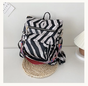 Détail du sac à dos zébré avec bandoulière tissée de style ethnique sur un tapis en paille