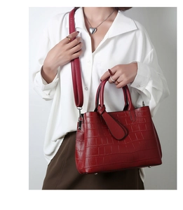 Detail of red crocodile embossed handbag with silver zipper and sturdy metal feet
