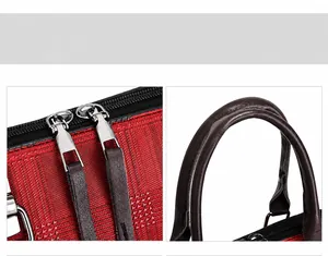 Detail of red and black textured tote bag featuring dual metal zippers and reinforced handles