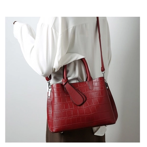 Model view of large deep red crocodile embossed tote bag worn as a crossbody shoulder bag