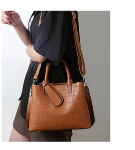 Close-up of brown crocodile embossed texture on synthetic leather tote bag detail
