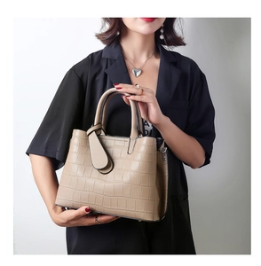 Detail of khaki crocodile pattern tote bag with double handles and decorative buckle