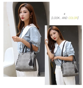 Lifestyle view of a grey plaid handbag with dark brown handles and a black tassel charm