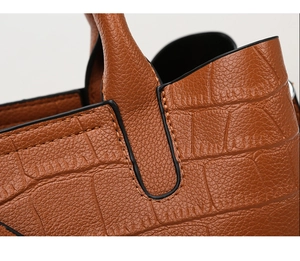 Detail of brown embossed leather bag showing precision stitching and black edge paint