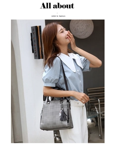 Close-up of grey plaid handbag featuring dark brown handles and stylish tassel decoration
