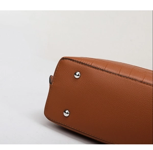 Detail of brown embossed leather bag bottom with silver protective metal feet studs