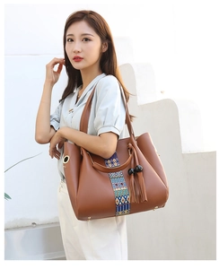 Sac fourre-tout en cuir marron avec ruban ethnique coloré et pompon sur le modèle