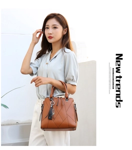 Detail of a brown tote bag with geometric embossed pattern and decorative tassel charm