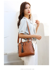 Detail of a brown leather shoulder bag with quilted stitching and decorative tassel pendant