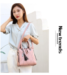 Pink quilted bag detail with black tassel and silver cat charm on light leather