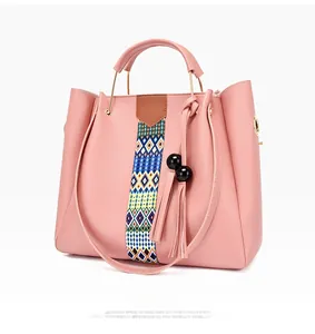 Détail latéral du sac seau rose avec sangle tissée et breloque à pompon noir élégant
