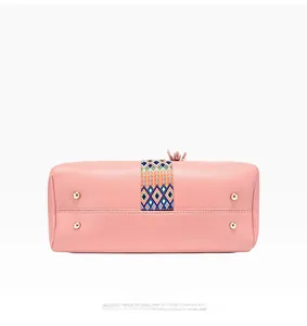 Détail de la base du sac en cuir rose avec pieds dorés et ruban ethnique