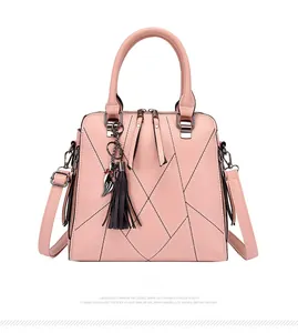 Detailed front view of light pink PU leather handbag with fringe and cat pendant charm
