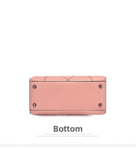 Detailed bottom view of pink leather bag featuring four protective metal studs and stitching
