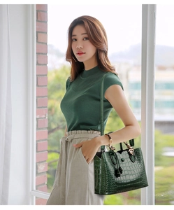 Detail of dark green crocodile pattern handbag with leopard print handle ribbon