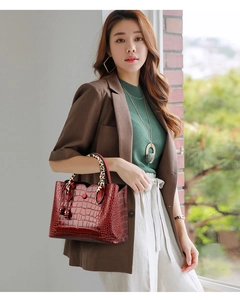 Close-up of burgundy crocodile pattern handbag with leopard print handle and plush charm