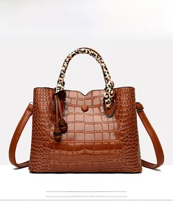 Front view of a brown crocodile pattern handbag with leopard scarf handle and tassel
