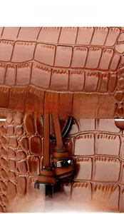 Detail of brown crocodile embossed leather bag with glossy finish and tassel pendant