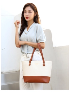 Detail of color-block tote bag in cream and tan synthetic leather with gold hardware