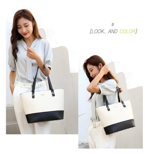 Close-up of elegant cream and black leather tote bag with protective metal bottom studs