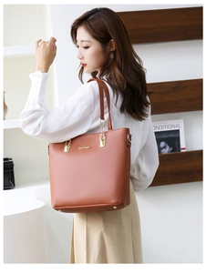 Sac cabas en cuir marron porté par un modèle avec des ferrures dorées et un style épuré