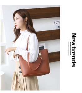 Sac fourre-tout en cuir marron avec détails dorés et chaîne porté par un mannequin