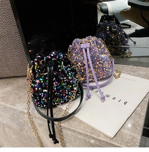 Close-up of black and purple sequin bucket bags with metallic chain straps and drawstring