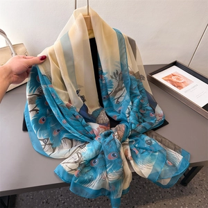 Elegant long chiffon scarf with blue peacock feather print on beige lightweight fabric