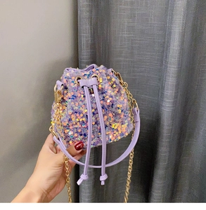 Close-up of sparkling purple sequin bucket bag with drawstring and golden chain strap