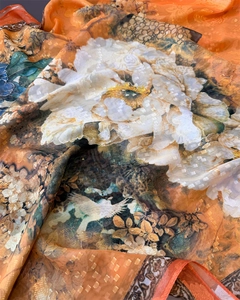 Detail of floral silk scarf showing peony and crane prints on orange jacquard fabric