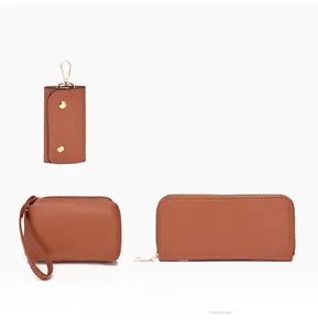Détail de l'ensemble en cuir marron avec portefeuille long, porte-clés et pochette bracelet
