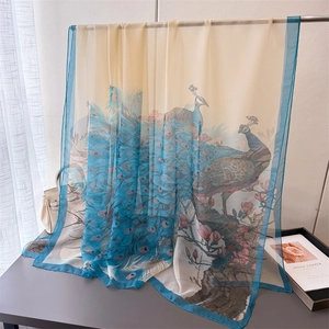 Close-up of soft floral silk scarf with peacock print and elegant blue borders