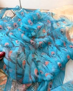 Detail of translucent blue peacock print silk scarf showing fabric texture and print quality