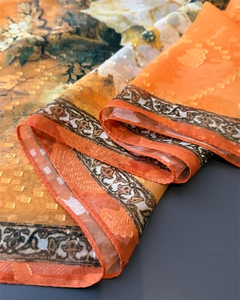 Close-up of warm orange silk scarf with peony floral print and jacquard texture