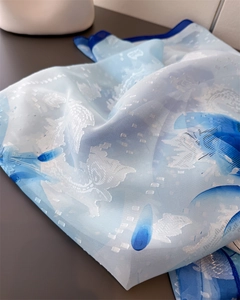 Detailansicht eines hellblauen Chiffonschals mit weicher Textur und Blumendruckmustern