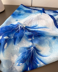Detailansicht des durchscheinenden blau-weißen Blumenmusters auf einem Seidenschal-Stoff