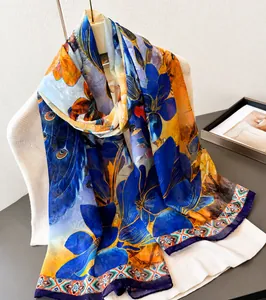 Detail eines eleganten Seidenschals mit Blumenmuster und orangefarbenen Akzenten am Bügel