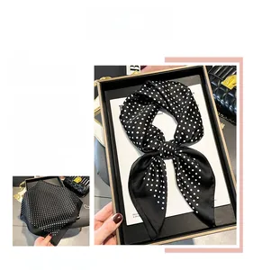 Detailed view of black and white polka dot silk scarf tied in a stylish bow knot
