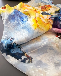 Detailansicht eines Schals mit Blumenmustern, blauen Schmetterlingen und Gitterstruktur