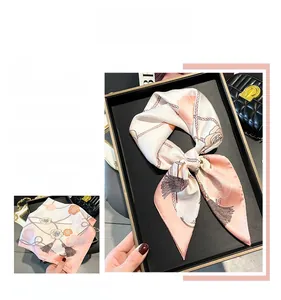 Detailed view of floral silk scarf with rose patterns and satin gloss on a tray