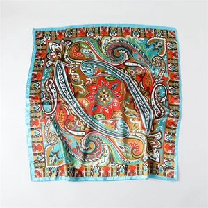 Detail of colorful paisley pattern on glossy satin silk scarf with sky blue borders