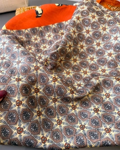 Detail eines Seidenschals mit Vintage-Geometriemuster und traditionellem Porträtdruck